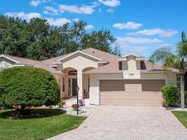 25243 River Crest Dr, Leesburg, FL 34748 - ranch-style house featuring a garage, decorative driveway, roof with shingles, and a front yard