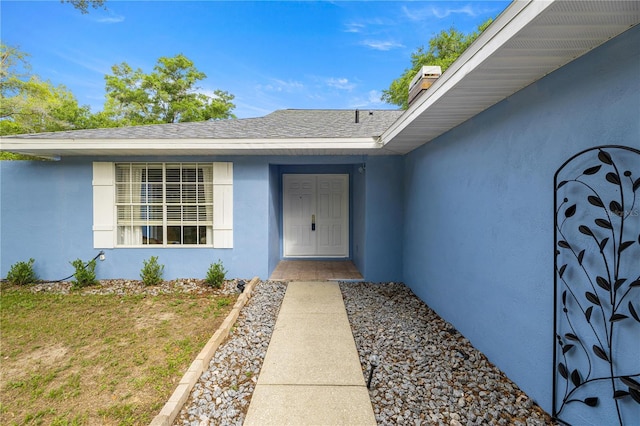 8180 N Duval Dr, Citrus Springs, FL 34434 - view of exterior entry featuring stucco siding and a shingled roof