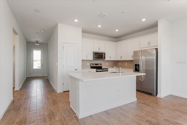 5017 Balsam Falls Rd, Deland, FL 32724 - kitchen featuring appliances with stainless steel finishes, a sink, light countertops, an island with sink, and white cabinetry
