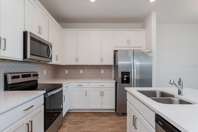 5017 Balsam Falls Rd, Deland, FL 32724 - kitchen featuring appliances with stainless steel finishes, a sink, white cabinets, tasteful backsplash, and recessed lighting
