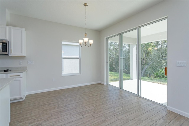 5009 Balsam Falls Rd, Deland, FL 32724 - kitchen featuring white cabinets, a chandelier, light wood-style flooring, pendant lighting, and stainless steel microwave