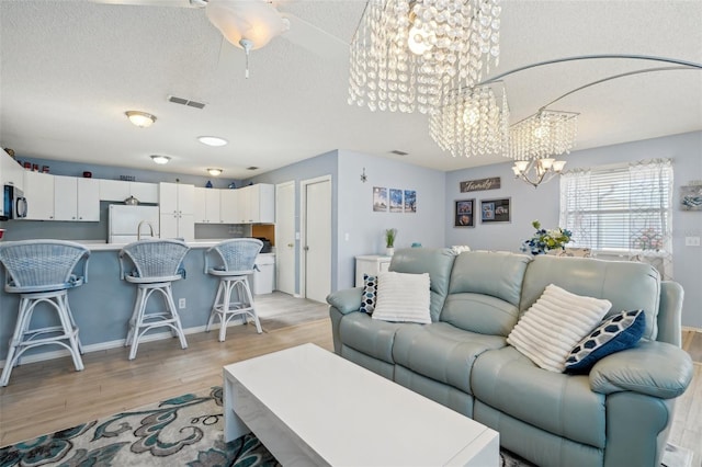 1728 Morelos Rd, The Villages, FL 32159 - living room featuring a chandelier, a textured ceiling, and light wood-type flooring