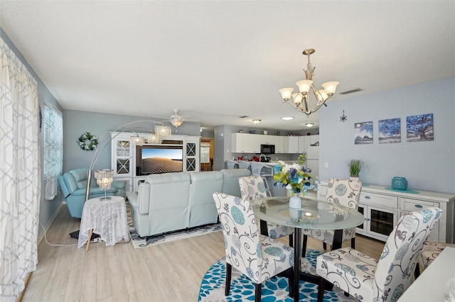 1728 Morelos Rd, The Villages, FL 32159 - dining room with a chandelier, light wood-style floors, and a ceiling fan