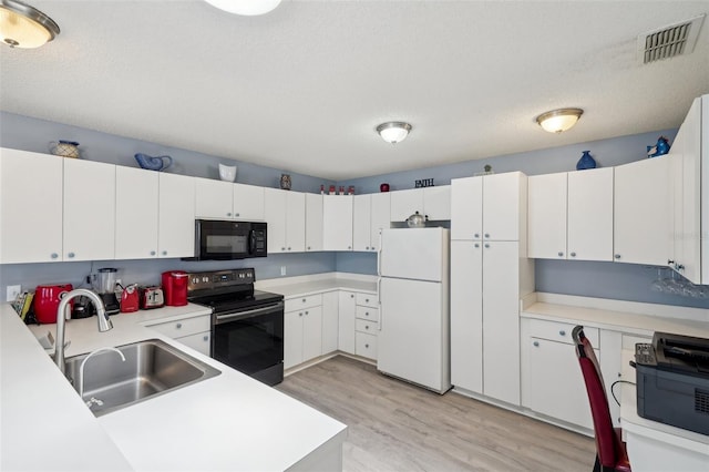 1728 Morelos Rd, The Villages, FL 32159 - kitchen featuring range with electric stovetop, freestanding refrigerator, black microwave, a sink, and light wood-style floors