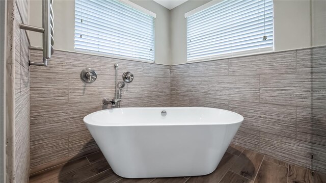 15245 Arabian Way, Montverde, FL 34756 - full bathroom with tile walls, a soaking tub, and wood tiled floors
