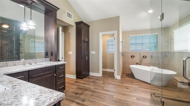 15245 Arabian Way, Montverde, FL 34756 - full bath with wood finished floors, vanity, a soaking tub, a shower stall, and baseboards