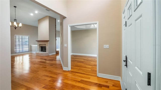 15245 Arabian Way, Montverde, FL 34756 - entryway featuring light wood-style floors, a towering ceiling, a brick fireplace, baseboards, and a chandelier
