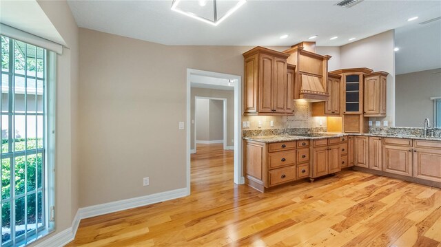 15245 Arabian Way, Montverde, FL 34756 - kitchen with backsplash, light stone countertops, light wood finished floors, and glass insert cabinets