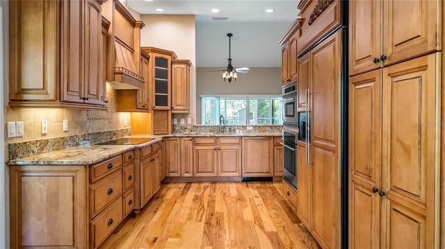 15245 Arabian Way, Montverde, FL 34756 - kitchen with oven, light wood-type flooring, black electric cooktop, a ceiling fan, and glass insert cabinets