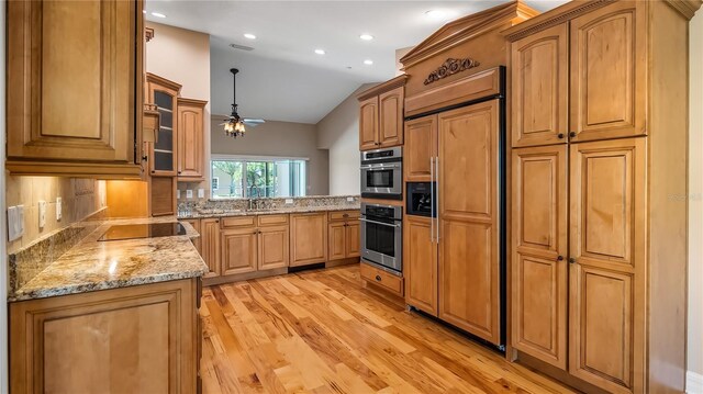 15245 Arabian Way, Montverde, FL 34756 - kitchen featuring stainless steel oven, light wood-style floors, lofted ceiling, paneled refrigerator, and light stone countertops