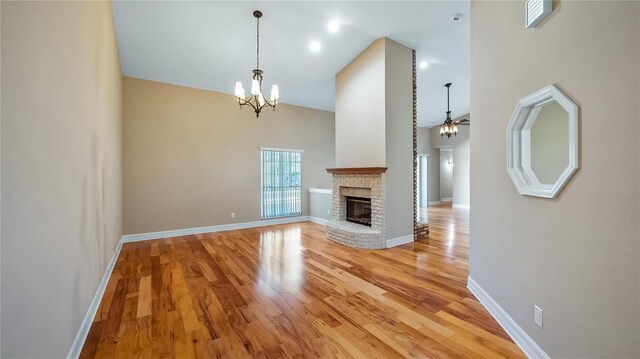 15245 Arabian Way, Montverde, FL 34756 - unfurnished living room featuring light wood finished floors, a chandelier, a ceiling fan, a fireplace, and a high ceiling