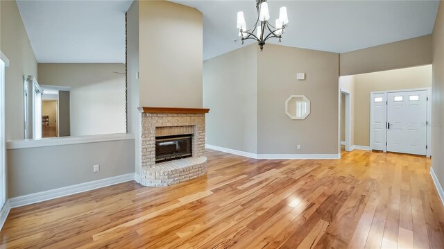 15245 Arabian Way, Montverde, FL 34756 - unfurnished living room with vaulted ceiling, a chandelier, light wood-style floors, a brick fireplace, and baseboards