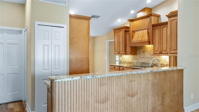15245 Arabian Way, Montverde, FL 34756 - kitchen with light stone countertops, custom range hood, backsplash, recessed lighting, and a peninsula