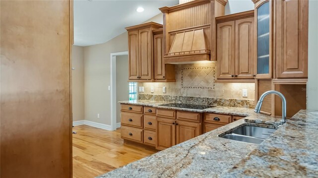 15245 Arabian Way, Montverde, FL 34756 - kitchen featuring a sink, black electric cooktop, light stone counters, light wood-type flooring, and baseboards