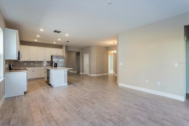 5036 Balsam Falls Rd, Deland, FL 32724 - kitchen featuring appliances with stainless steel finishes, open floor plan, light wood finished floors, light countertops, and an island with sink