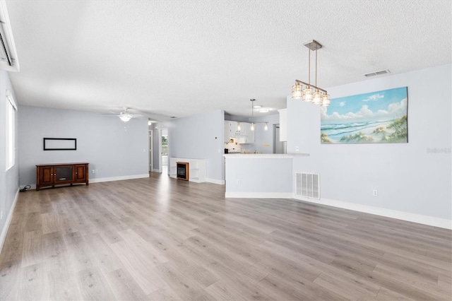 1615 Navidad St, The Villages, FL 32162 - unfurnished living room with a ceiling fan, light wood-style floors, a textured ceiling, and baseboards