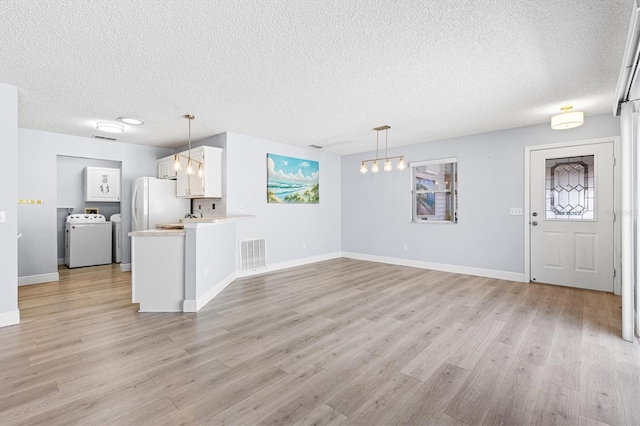 1615 Navidad St, The Villages, FL 32162 - unfurnished living room with washer / clothes dryer, a textured ceiling, light wood finished floors, baseboards, and a chandelier