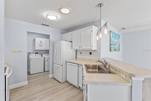 1615 Navidad St, The Villages, FL 32162 - kitchen featuring a sink, independent washer and dryer, white appliances, light wood-style flooring, and a peninsula