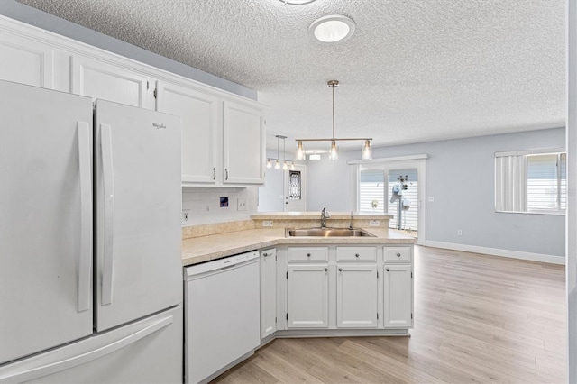 1615 Navidad St, The Villages, FL 32162 - kitchen with white appliances, a sink, a peninsula, a textured ceiling, and light countertops
