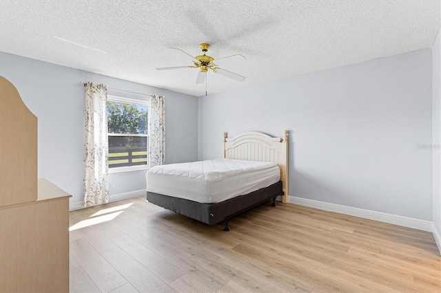 1615 Navidad St, The Villages, FL 32162 - bedroom featuring light wood-style floors, baseboards, a textured ceiling, and a ceiling fan