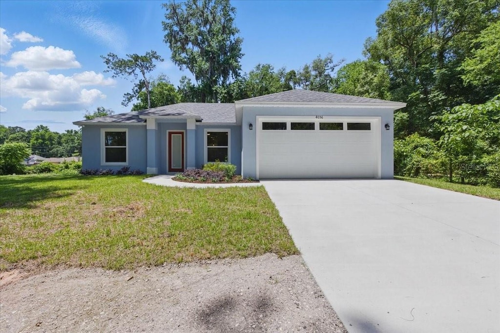 4056 SW 18th St, Gainesville, FL 32608 - ranch-style house featuring an attached garage, a front yard, concrete driveway, stucco siding, and roof with shingles