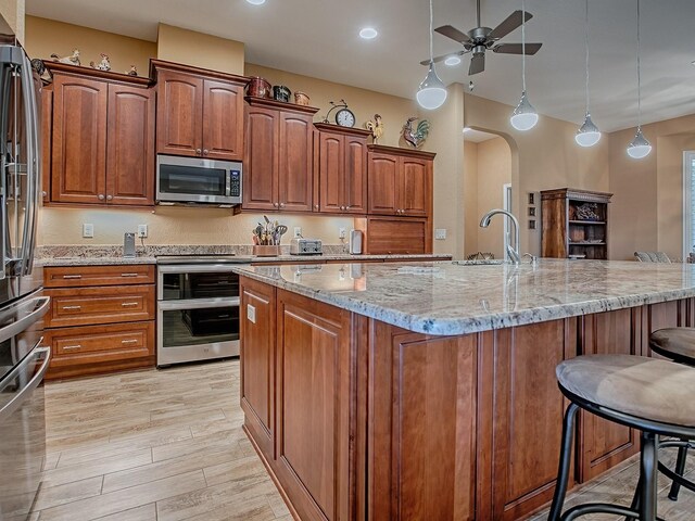 10994 SE 168th Loop, Summerfield, FL 34491 - kitchen featuring stainless steel microwave, a sink, a kitchen bar, ceiling fan, and light stone counters
