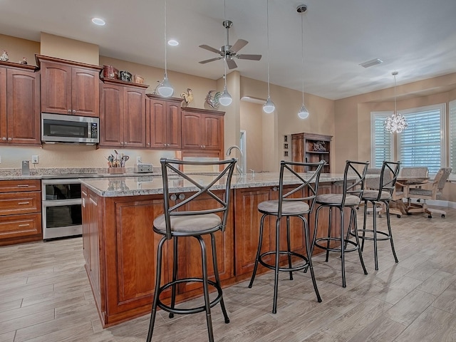 10994 SE 168th Loop, Summerfield, FL 34491 - kitchen with stainless steel microwave, oven, ceiling fan, light wood-style flooring, and a kitchen bar