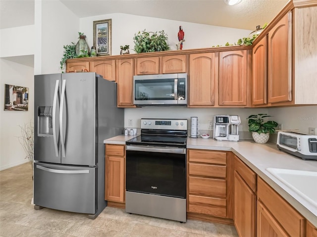 1713 Jadestone Ter, The Villages, FL 32162 - kitchen featuring appliances with stainless steel finishes, light countertops, lofted ceiling, a sink, and brown cabinetry