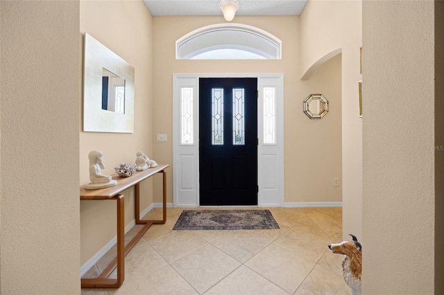 entrance foyer with arched walkways, light tile patterned floors, and baseboards