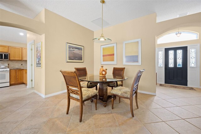 dining area featuring light tile patterned flooring, a textured ceiling, and baseboards