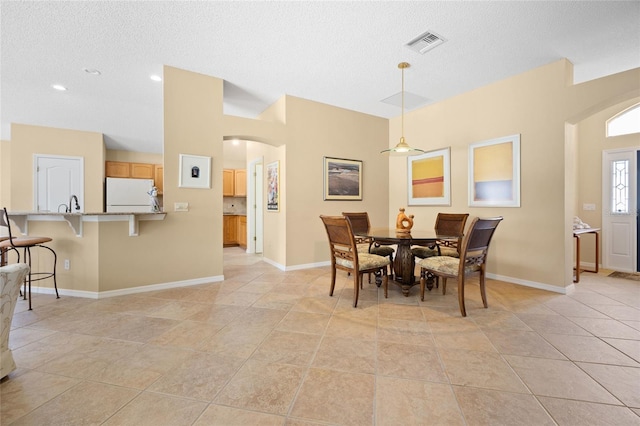 dining space with arched walkways, a textured ceiling, and baseboards