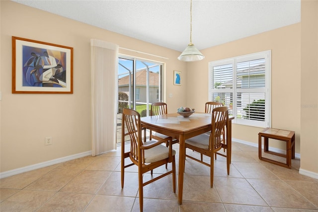 dining space with light tile patterned flooring, healthy amount of natural light, baseboards, and a textured ceiling