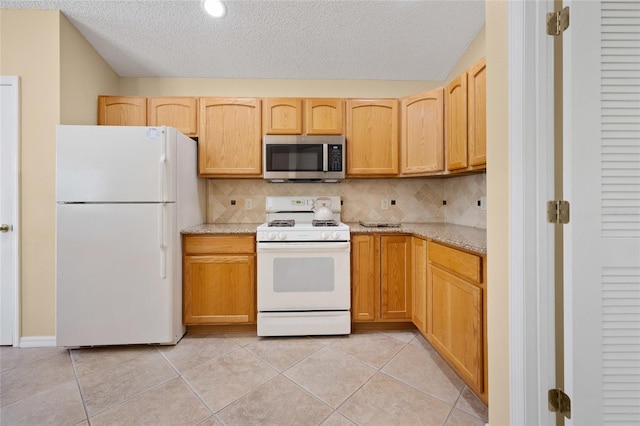 kitchen with white appliances, tasteful backsplash, a textured ceiling, light stone counters, and light tile patterned floors