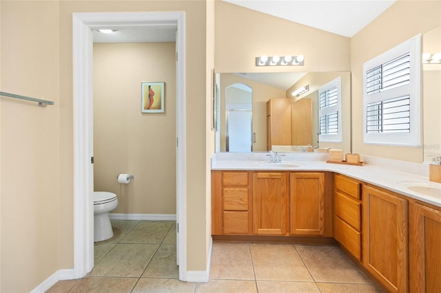 bathroom with tile patterned flooring, toilet, double vanity, vaulted ceiling, and baseboards