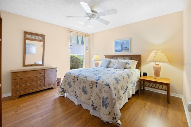 bedroom featuring wood finished floors, a ceiling fan, baseboards, and a textured ceiling