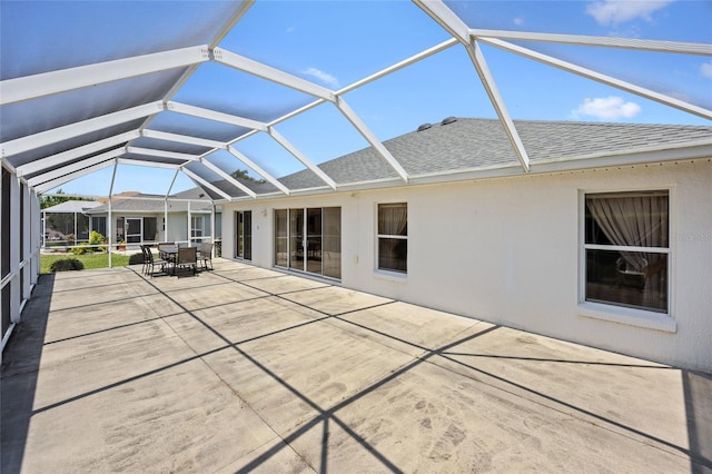 back of house with a shingled roof, a patio area, outdoor dining space, and glass enclosure