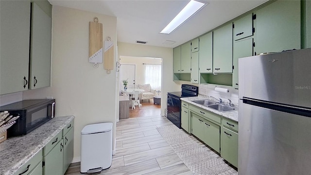 kitchen featuring black appliances, a sink, green cabinetry, and light countertops