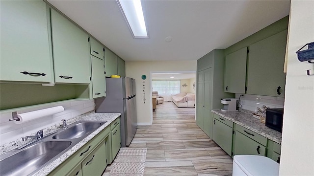 kitchen with green cabinets, a sink, freestanding refrigerator, and black microwave