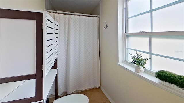 full bath featuring toilet, tile patterned flooring, and a shower with curtain