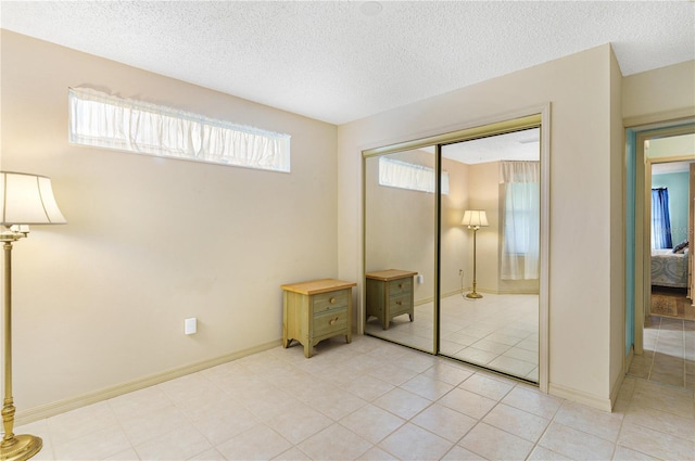 735 Palma Dr, The Villages, FL 32159 - unfurnished bedroom with a closet, a textured ceiling, light tile patterned flooring, and baseboards