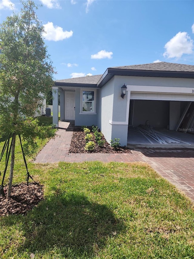 1808 Carnostie Rd, Winter Haven, FL 33884 - view of front facade featuring stucco siding, decorative driveway, a front lawn, and a garage