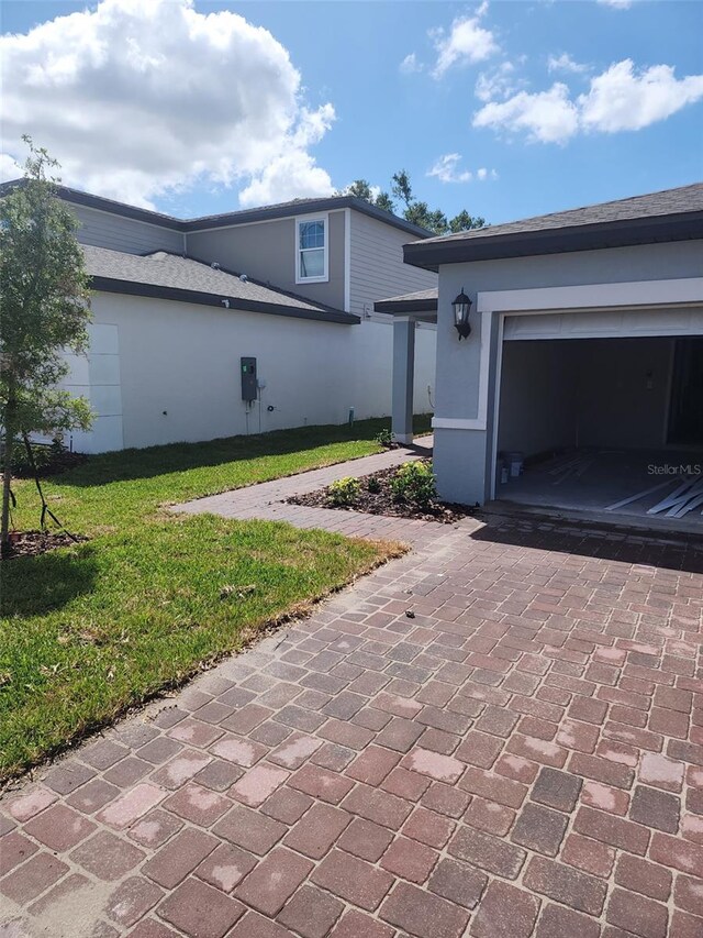 1808 Carnostie Rd, Winter Haven, FL 33884 - view of side of property featuring decorative driveway, a yard, an attached garage, and stucco siding