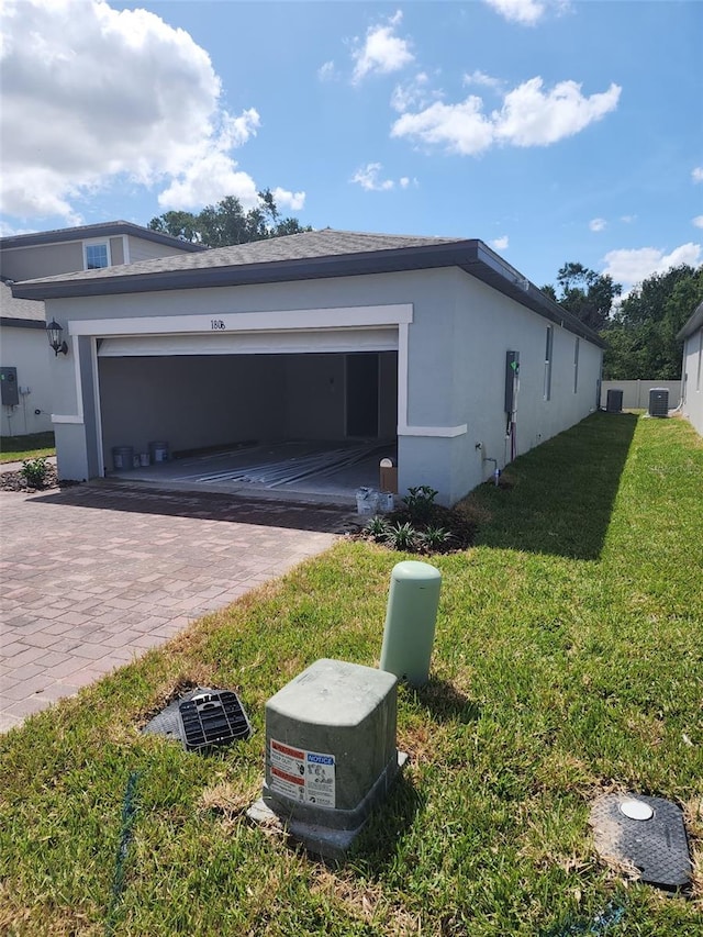 1808 Carnostie Rd, Winter Haven, FL 33884 - view of side of property with stucco siding, a yard, decorative driveway, and a garage
