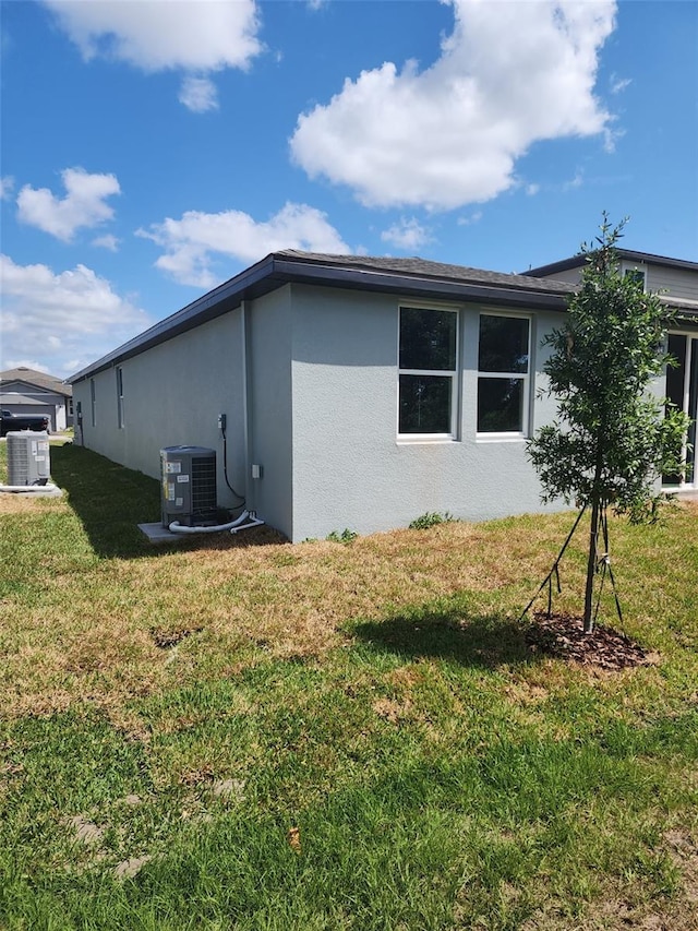 1808 Carnostie Rd, Winter Haven, FL 33884 - view of home's exterior featuring stucco siding, central AC, and a lawn