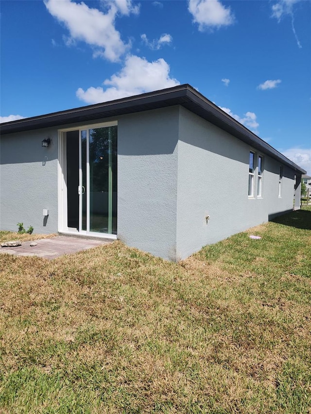1808 Carnostie Rd, Winter Haven, FL 33884 - back of house featuring stucco siding, a lawn, and a patio area