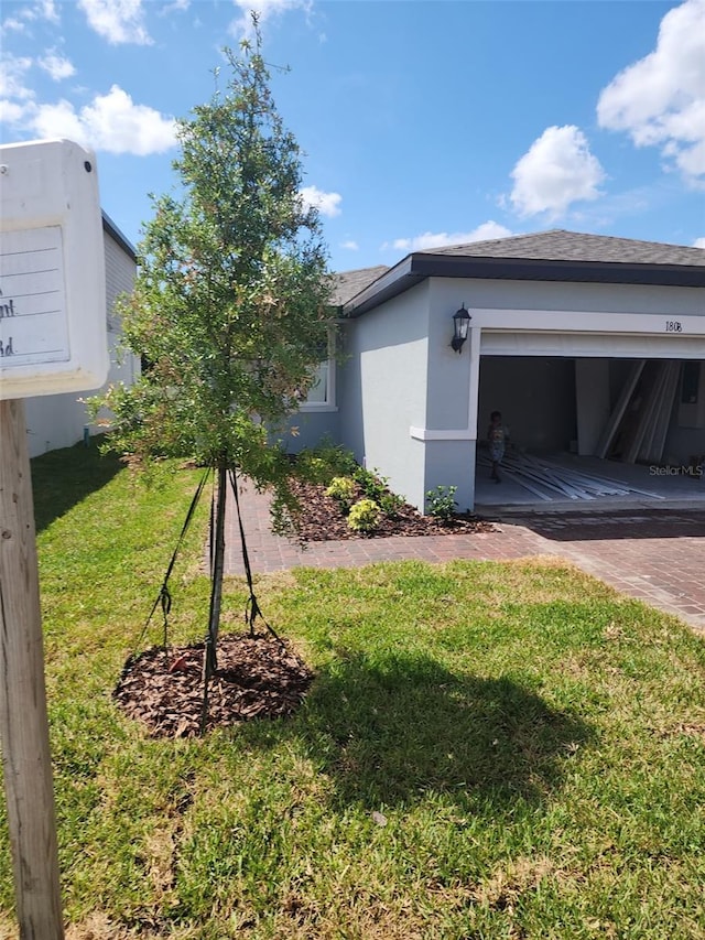 1808 Carnostie Rd, Winter Haven, FL 33884 - view of side of home with stucco siding, a lawn, decorative driveway, and a garage