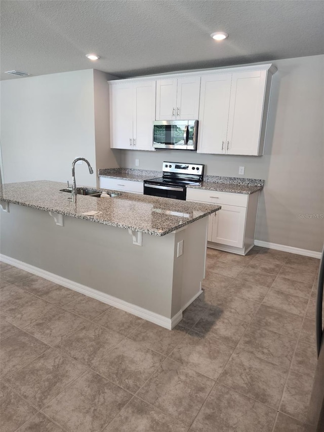1808 Carnostie Rd, Winter Haven, FL 33884 - kitchen with stainless steel appliances, a sink, a textured ceiling, white cabinets, and light stone countertops