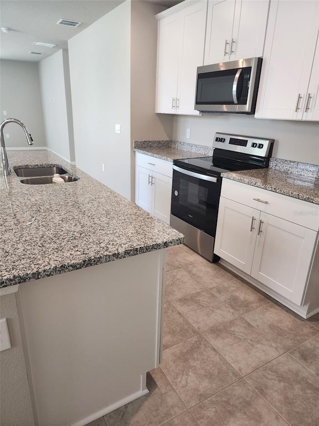 1808 Carnostie Rd, Winter Haven, FL 33884 - kitchen with appliances with stainless steel finishes, a sink, light stone countertops, and white cabinetry