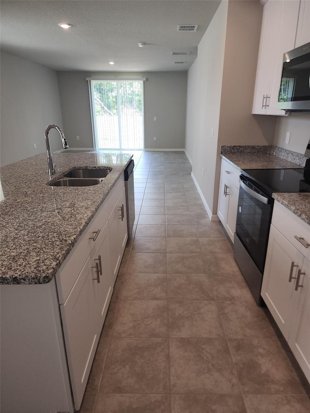 1808 Carnostie Rd, Winter Haven, FL 33884 - kitchen featuring appliances with stainless steel finishes, a sink, white cabinets, dark stone countertops, and a textured ceiling