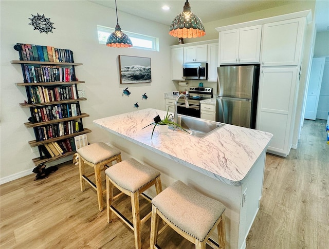 12077 Lakeshore Way, Oxford, FL 34484 - kitchen featuring stainless steel appliances, a sink, white cabinetry, light wood-style floors, and a kitchen bar